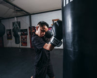variant:Black/White::TITLE Premier Leather Super Bag Gloves 2.0 in use with a heavy bag