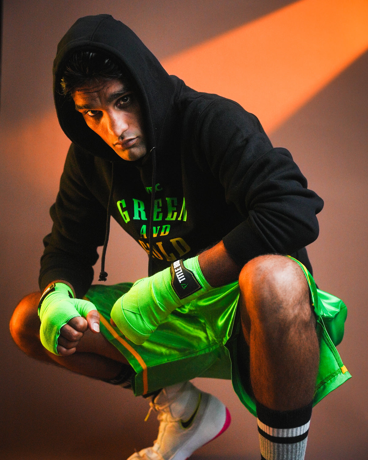 variant:lifestyle::WBC By TITLE Boxing Green & Gold Hoodie on boxer with hood up kneeled in boxing stance