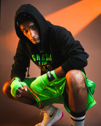 variant:lifestyle::WBC By TITLE Boxing Green & Gold Hoodie on boxer with hood up kneeled in boxing stance