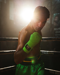 variant:Green/Black::WBC by TITLE Boxing Hand Wraps on boxer's hand in boxing stance in ring