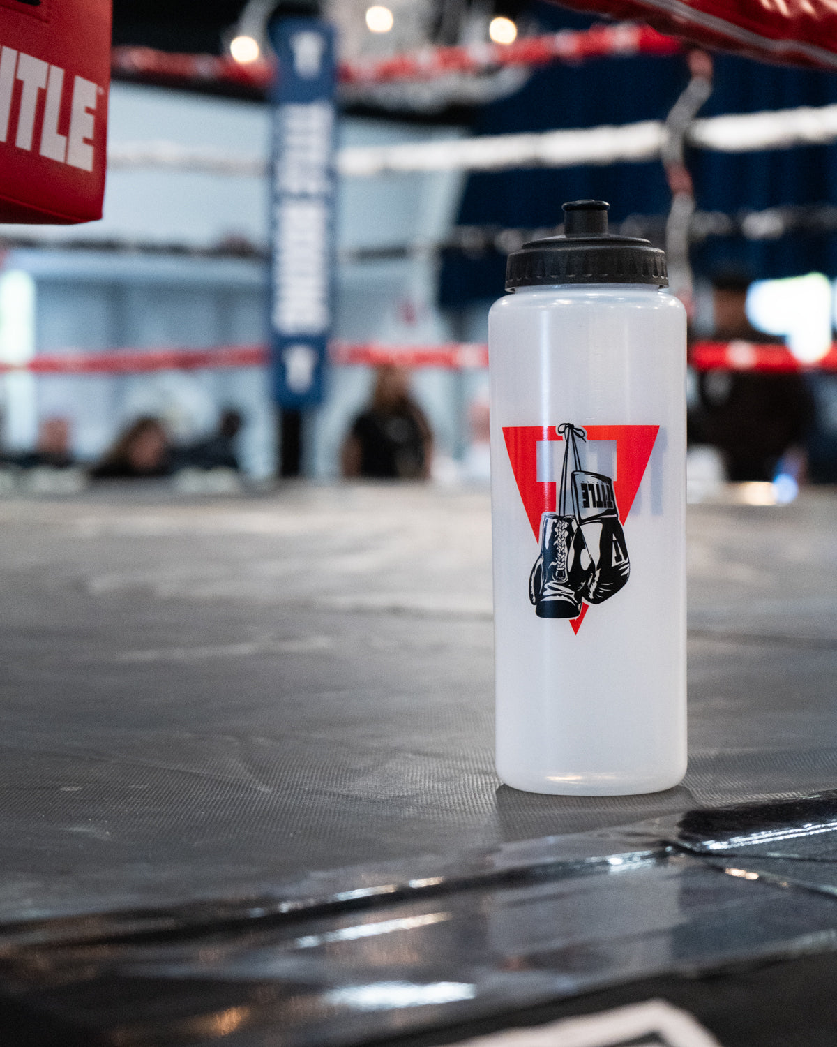 variant:lifestyle::TITLE Boxing Pro Plus Water Bottle on the side of a boxing ring