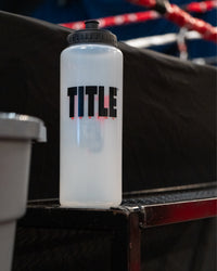 variant:lifestyle::TITLE Boxing Pro Plus Water Bottle on the steps of a boxing ring