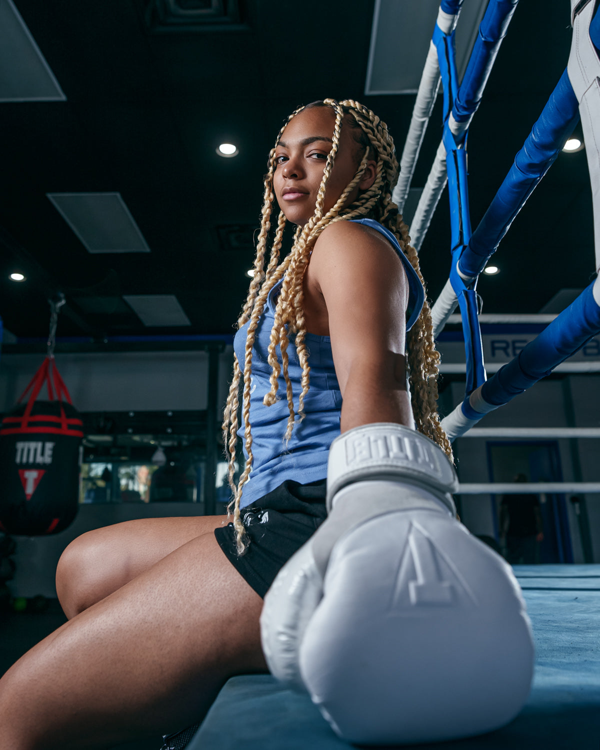 variant:lifestyle::TITLE White Boxing Pro Bag Gloves  girl sitting on ring