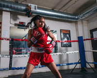 variant:Red/Blue::TITLE boxing Women's Reversible Elite Amateur boxing set red side on female fighter in the ring