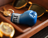 variant:blue::TITLE Boxing Excel Glove Keyring  laying down next to glasses