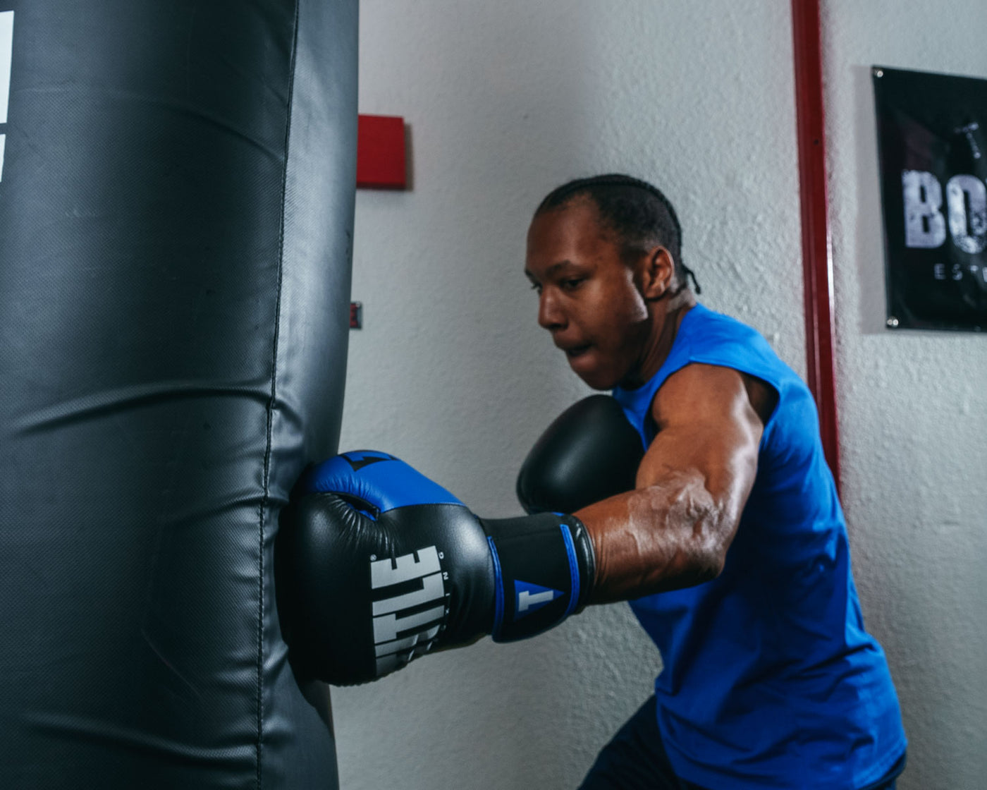variant:Black/Blue::TITLE Boxing Dynamic Strike Heavy Bag Gloves man hitting heaving bag left jab