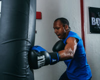 variant:Black/Blue::TITLE Boxing Dynamic Strike Heavy Bag Gloves man hitting heaving bag left jab