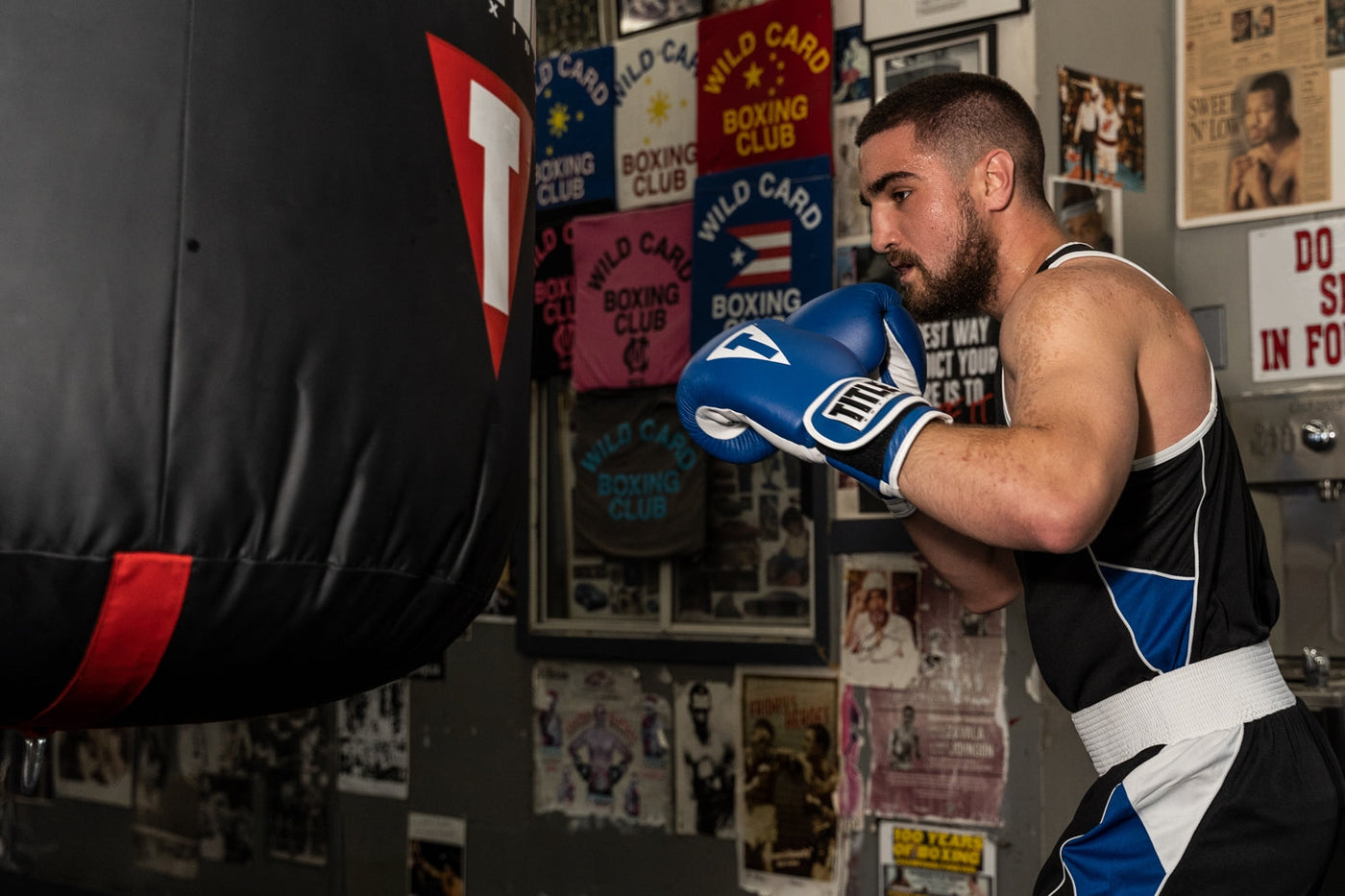 variant:Blue/White::TITLE Boxing Pro Style Leather Training Gloves 3.0 man about to punch a bag