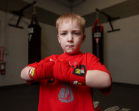 variant:red::BOOM BOOM Boxing Youth Flex Hand Wraps kid hands together in front of bags