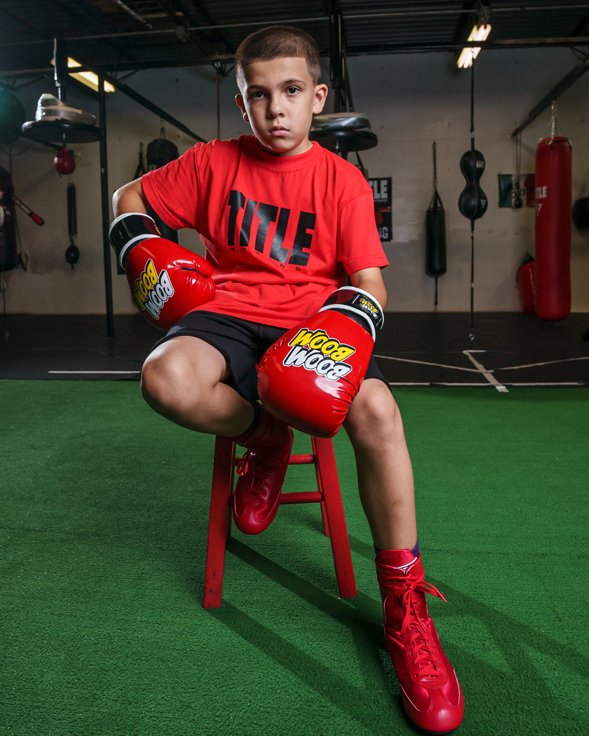 variant:Red/Black::BOOM BOOM Boxing Striker Youth Boxing Gloves boy sitting on stool