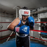 variant:white::TITLE Classic USA Boxing Competition Headgear – Open Face kid with blue gloves in ring