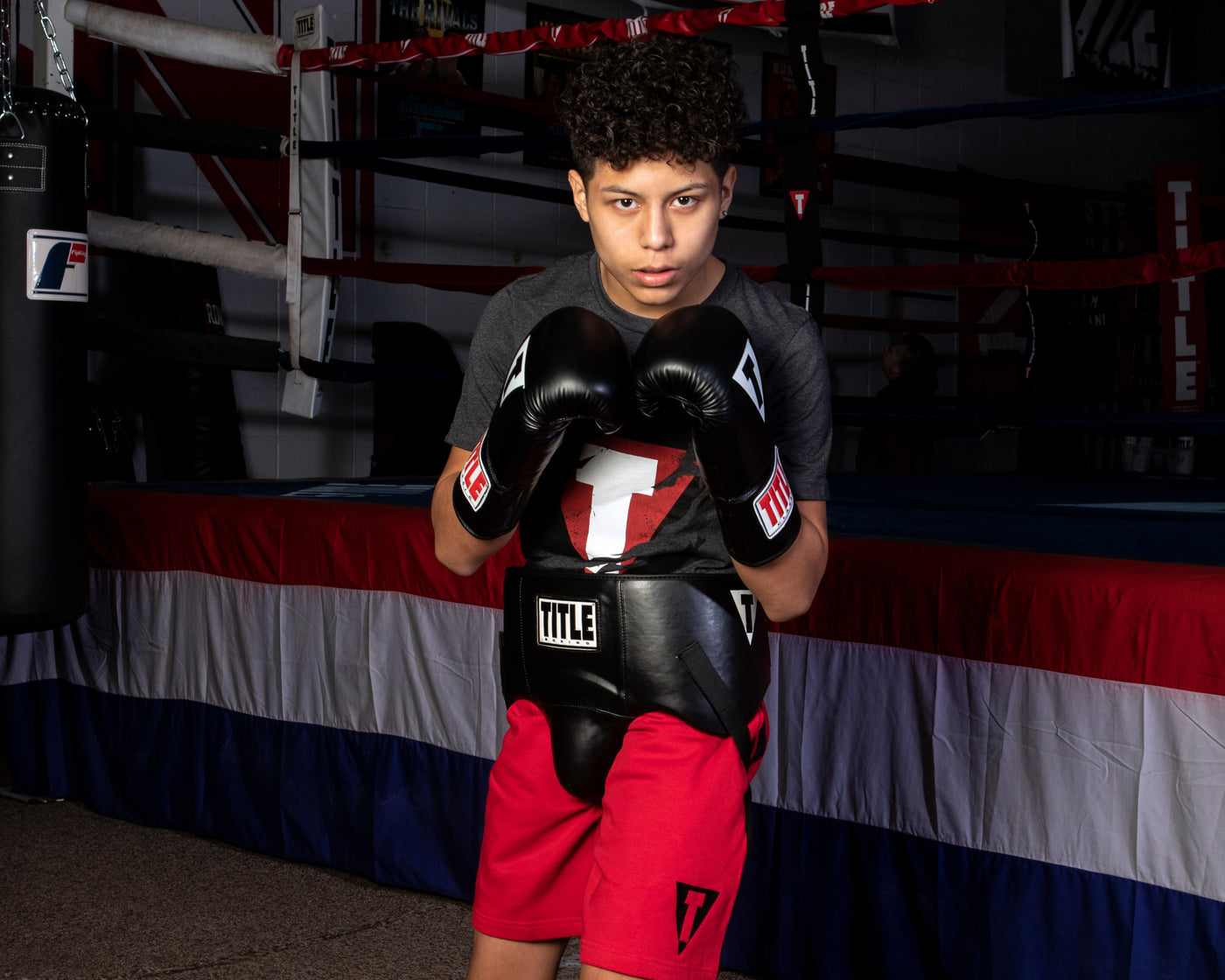 variant:black::TITLE Classic Super Bag Gloves 2.0 kid wearing protective cup and gloves