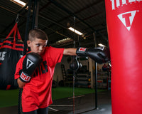 variant:black::TITLE Classic Super Bag Gloves 2.0 kid hitting a red bag