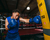 variant:blue/black::TITLE Boxing Dauntless Training Gloves close up of guy hitting bag jab