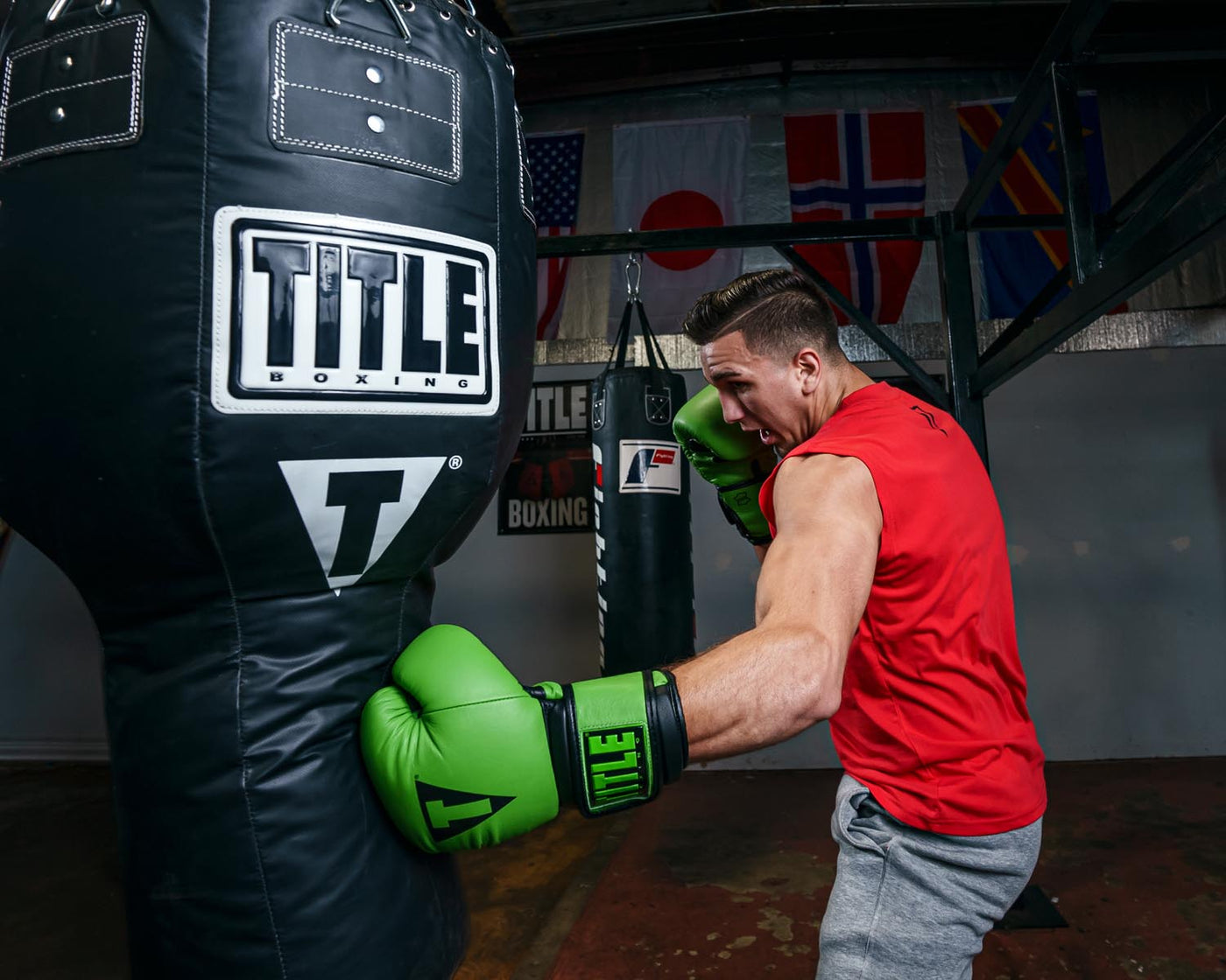 variant:green/black::TITLE Boxing Dauntless Training Gloves guy hitting bag left jab