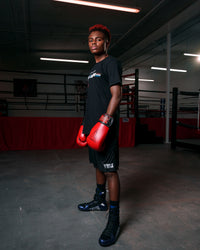 variant:black::Fighting S2 GEL Superior Boxing Shoes guy stading with rings in background