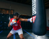 variant:lifestyle::TITLE Boxing Gel World V2T Limited Edition Autism Awareness Bag Gloves guy wearing boxing gloves hitting heavy bag