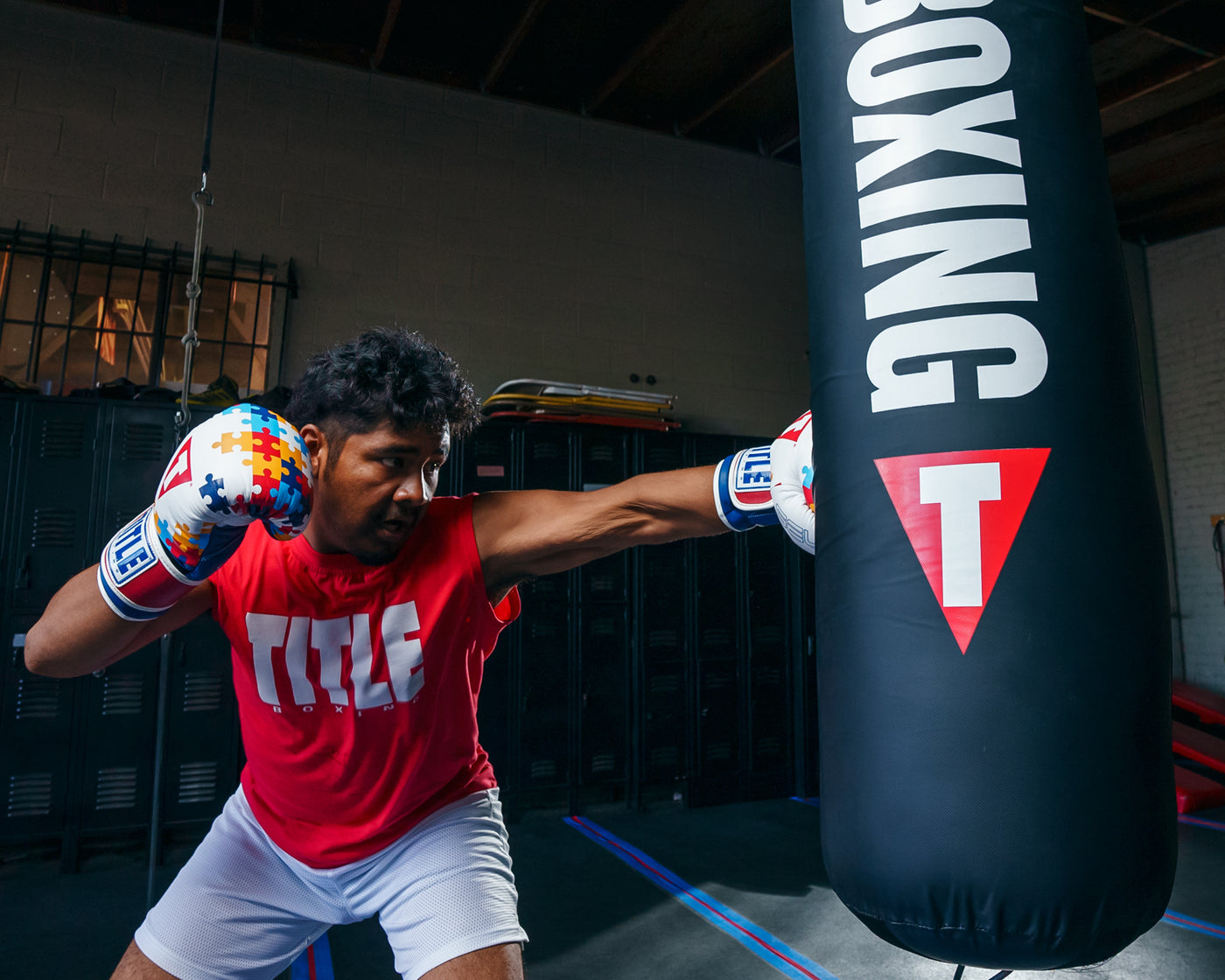 variant:lifestyle::TITLE Boxing Gel World V2T Limited Edition Autism Awareness Bag Gloves guy with boxing gloves hitting punching bag