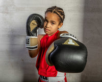 variant:black/gold/white::TITLE Boxing Gel World V2T Bag Gloves kid posing with boxing gloves