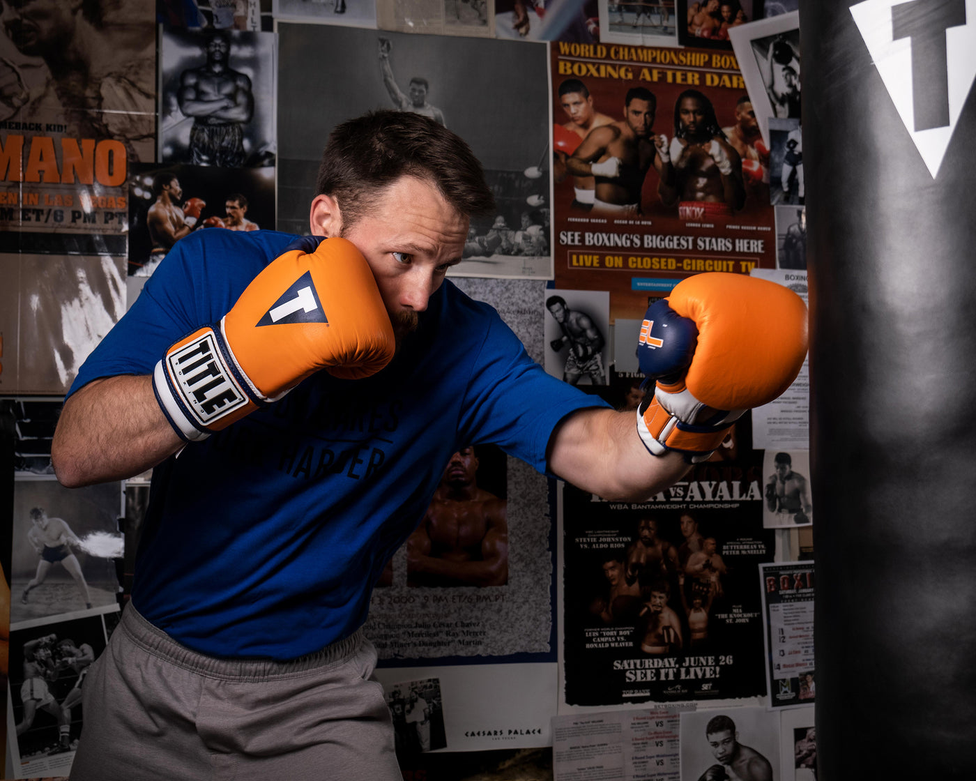 variant:orange::TITLE Boxing Gel World V2T Bag Gloves guy wearing boxing gloves hitting heavy bag