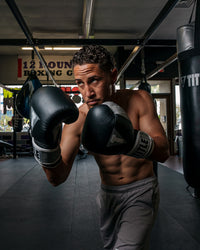 variant:black/silver::TITLE Boxing Gel World V2T Bag Gloves guy posing with boxing gloves in boxing gym