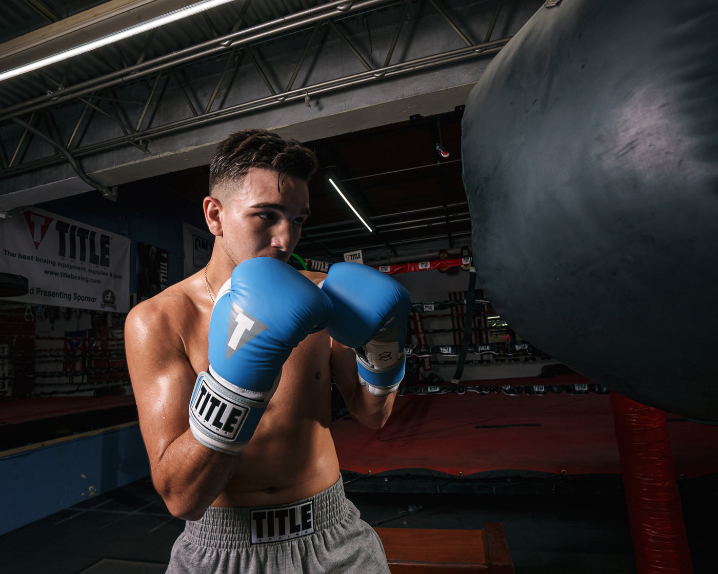 variant:light blue/white::TITLE Boxing Gel World V2T Bag Gloves guy with boxing gloves and heavy bag in gym