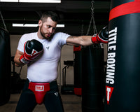 variant:red/black::TITLE Boxing Infused Foam Interrogate Training Gloves 2.0 guy wearing boxing gloves punching heavy bag