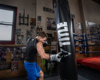 variant:silver/black::TITLE Boxing Infused Foam Interrogate Training Gloves 2.0 guy wearing boxing gloves punching heavy bag in boxing gym