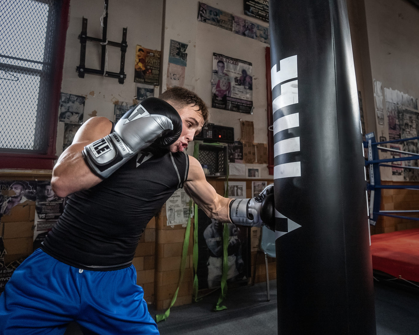 variant:silver/black::TITLE Boxing Infused Foam Interrogate Training Gloves 2.0 guy wearing boxing gloves punching heavy bag