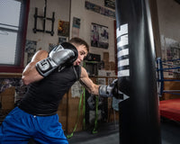 variant:silver/black::TITLE Boxing Infused Foam Interrogate Training Gloves 2.0 guy wearing boxing gloves punching heavy bag