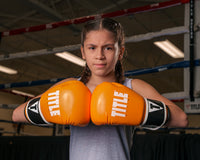 variant:orange/black::TITLE Boxing Instinct Fitness Bag Gloves girl posing with boxing gloves