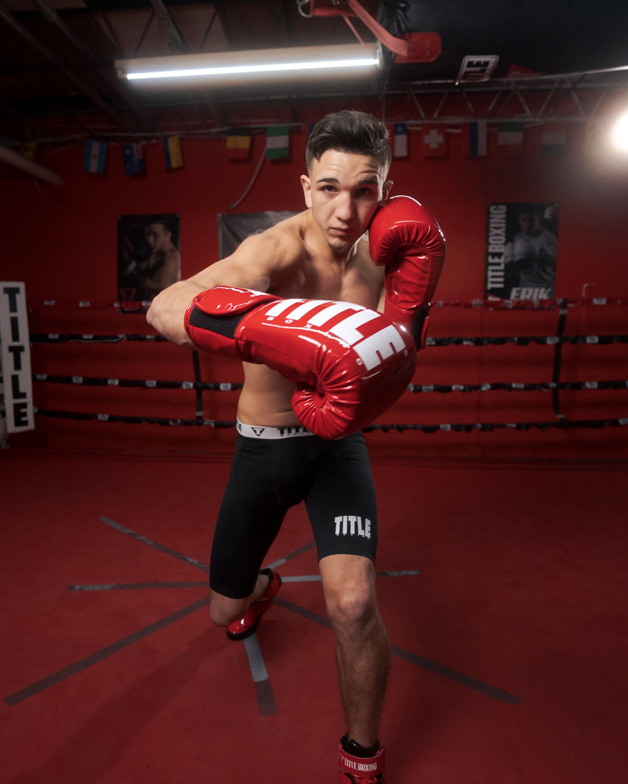 variant:Red/White::TITLE Boxing Inferno Intensity Elastic Training Gloves man wearing gloves posing