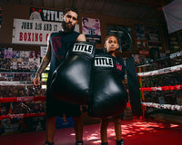 variant:black::TITLE Boxing Jumbo Boxing Gloves 2.0 guy and kid posing with jumbo boxing gloves in boxing ring