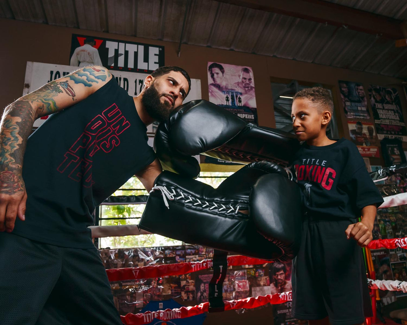 variant:black::TITLE Boxing Jumbo Boxing Gloves 2.0 guy and kid posing with jumbo boxing gloves in boxing ring