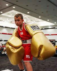 variant:gold::TITLE Boxing Jumbo Boxing Gloves 2.0 kid posing with jumbo boxing gloves