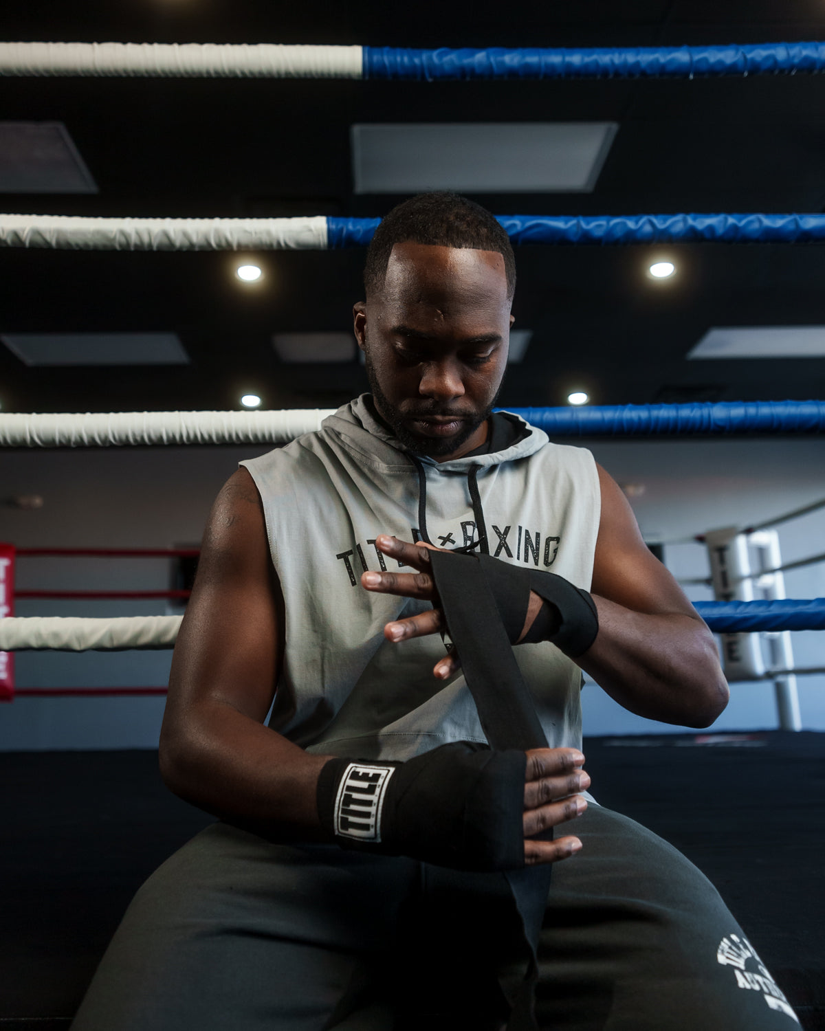 variant:Black::TITLE Boxing Mexican Style 180" Hand Wraps guy sitting wrapping hands with hand wraps