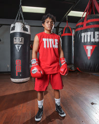 variant:Red/White::Pro Mex Professional Lace Sparring Gloves V3.0 kid standing between 3 bags