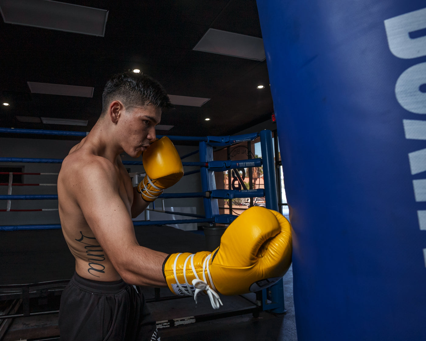 variant:Yellow/Black::Pro Mex Professional Lace Sparring Gloves V3.0 guy hitting bag right hook