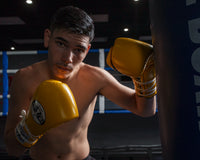variant:Yellow/Black::Pro Mex Professional Lace Sparring Gloves V3.0 kid posing left hand on bag