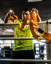 variant:gold::TITLE Boxing Select 180" Semi Elastic Mexican Hand Wraps guy rolling out wrap
