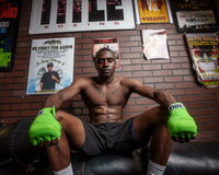 variant:neon lime::TITLE Boxing Select 180" Semi Elastic Mexican Hand Wraps guy sitting on heavy bag