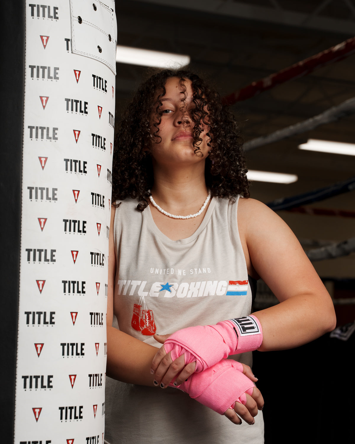 variant:neon pink::TITLE Boxing Select 180" Semi Elastic Mexican Hand Wraps girl standing by heavy bag