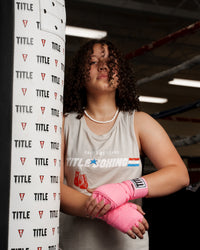 variant:neon pink::TITLE Boxing Select 180" Semi Elastic Mexican Hand Wraps girl standing by heavy bag