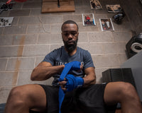 variant:royal::TITLE Boxing Select 180" Semi Elastic Mexican Hand Wraps guy sitting down putting on wraps