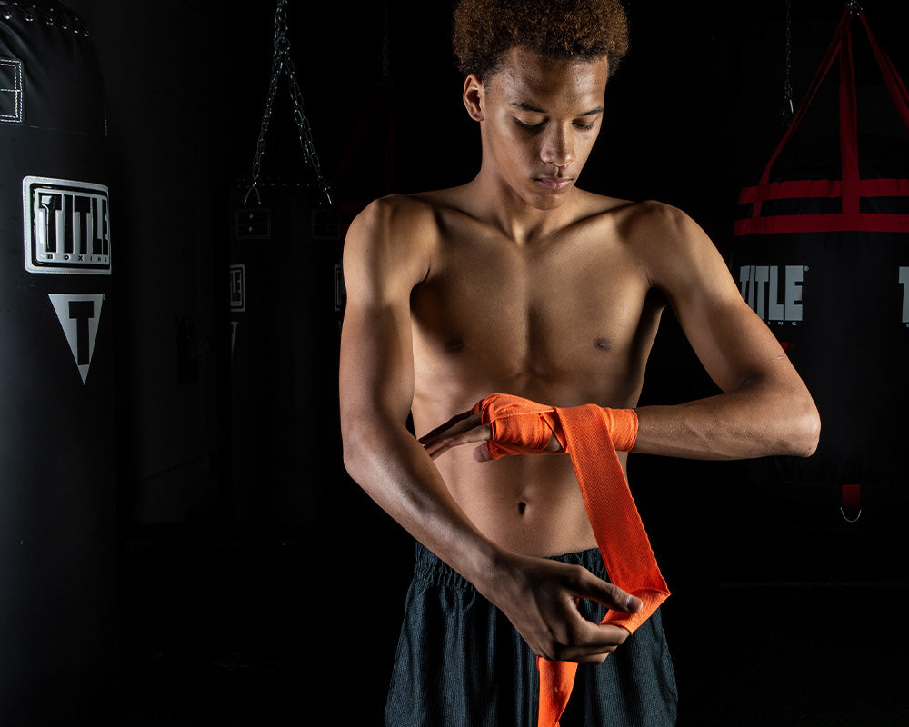 variant:orange::TITLE Boxing Select 180" Semi Elastic Mexican Hand Wraps guy puttin gon wrap 
