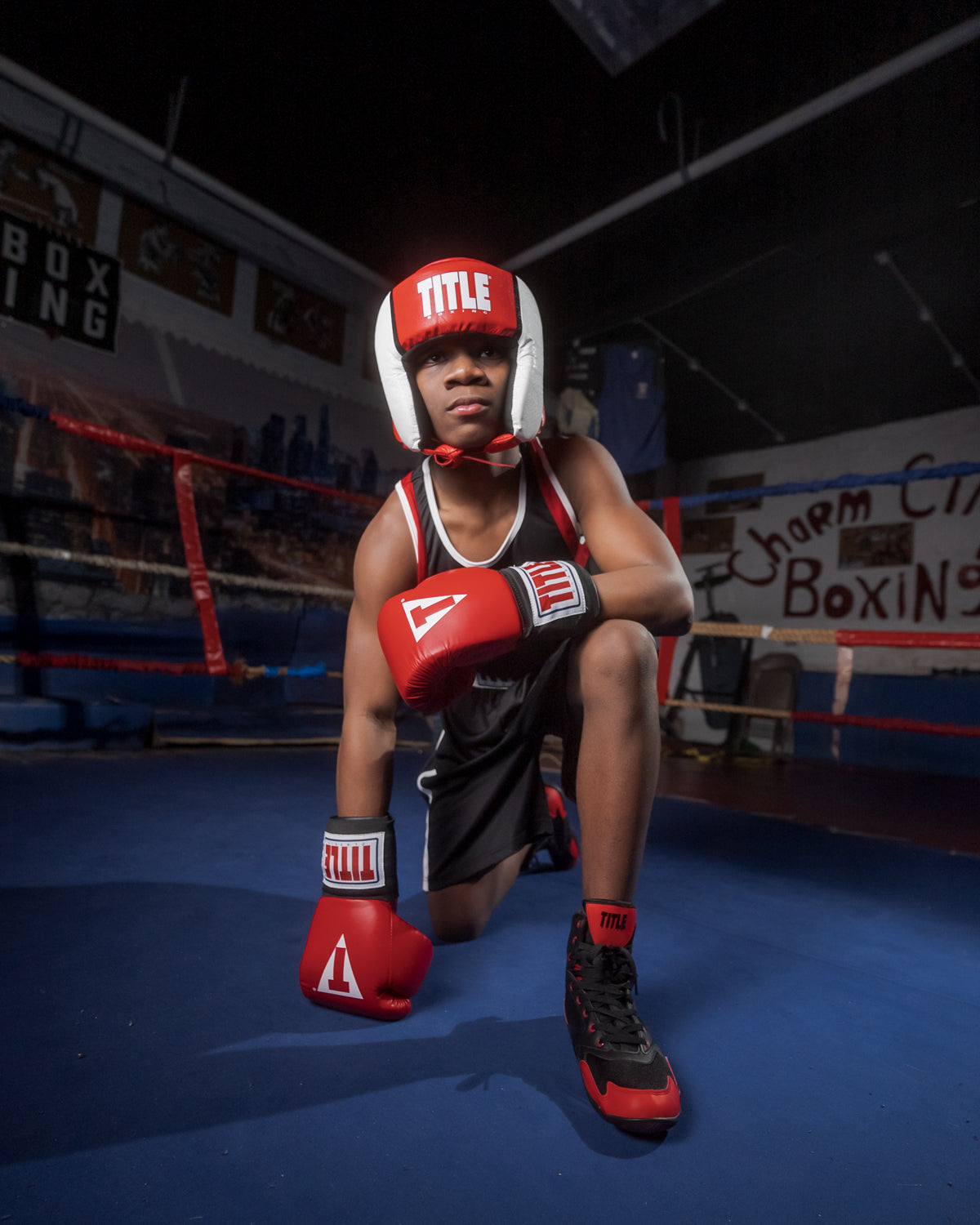 variant:black/red::TITLE Charged Boxing Shoes kid kneeling with shoes on
