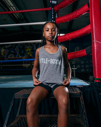 variant:Grey::TITLE Boxing Women's Ogio Luuma Tank girl posing sitting on boxing ring