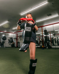 variant:lifestyle::TITLE Boxing Vinyl Shin-Instep Guards 2.0 girl blocking with guards