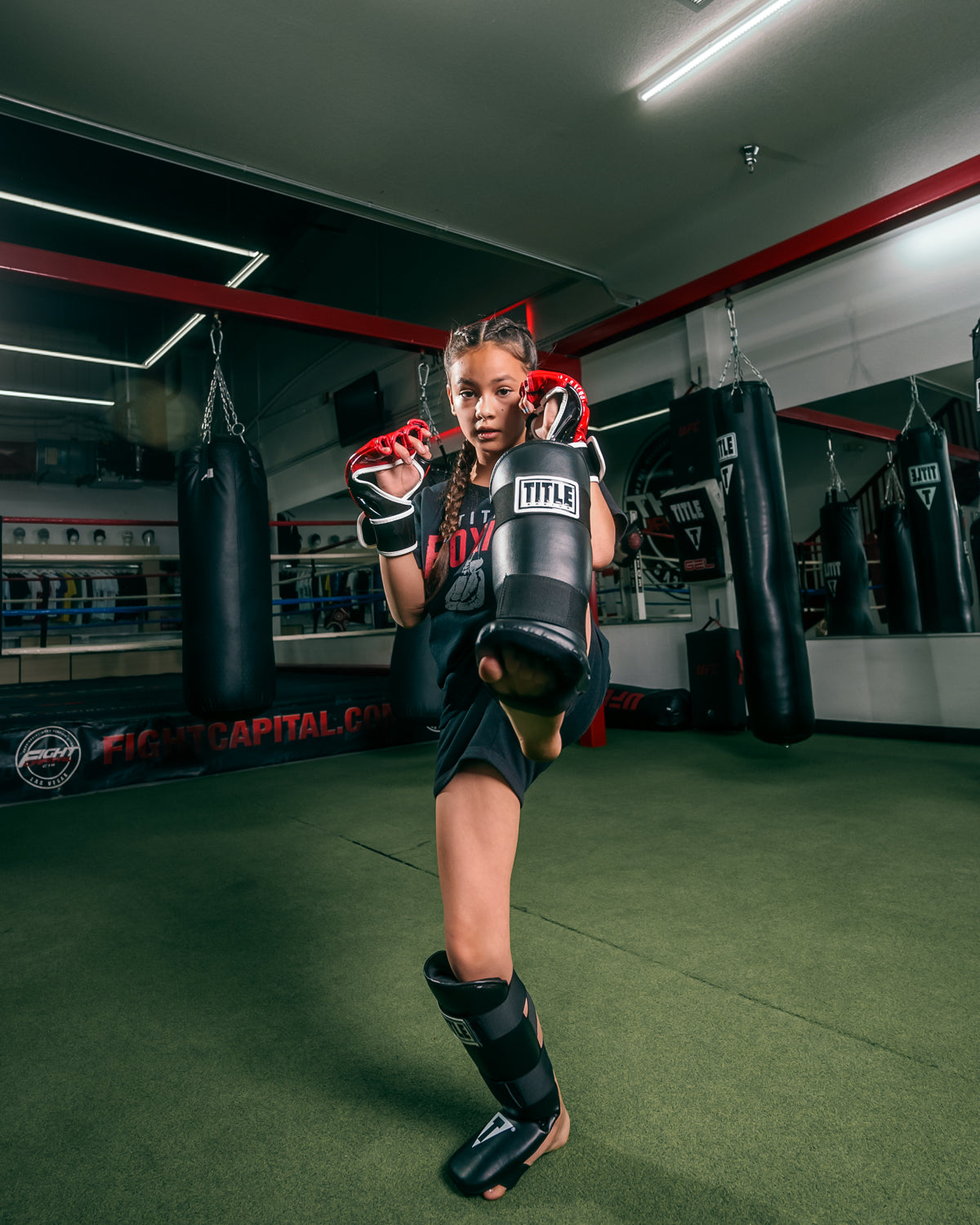 variant:lifestyle::TITLE Boxing Vinyl Shin-Instep Guards 2.0 girl blocking with leg up