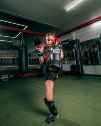 variant:lifestyle::TITLE Boxing Vinyl Shin-Instep Guards 2.0 girl blocking with leg up